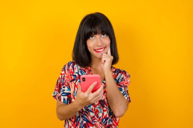 Güzel bir kadının cep telefonuyla arka planda akıllı telefon tuttuğunu hayal ediyorum.