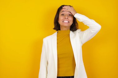 Tüh, ne yaptım ben? Güzel esmer iş kadını sarı arka plan karşısında korkmuş ve pişmanlık dolu bir ifadeyle el ele tutuşuyor.. 