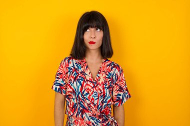 Şaşırmış genç, şaşkın, beyaz bir kadının kızıl saçlı, günlük kıyafetler giyip dudaklarını kıvıran ve önünde korkunç bir şey gören fotoğrafı.