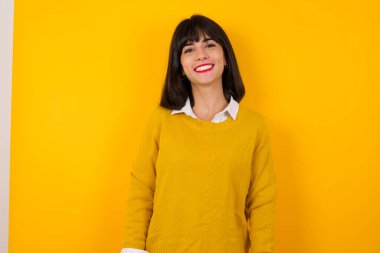 Sarı stüdyo arka planında poz veren güzel esmer kadın.