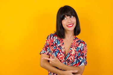 Kamerada poz veren güzel esmer kadın. İnce görünüşlü ve el kol hareketi yapan. Bayan tasarımcı, işaret parmağıyla harika bir ürün sunuyor. Hareket kavramı.