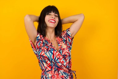 Güven ve cinsel ilişki konsepti. Çekici genç iş kızı portresi, kendine güvenen bir ifadeyle gülümseyen ve ellerini başının üstünde tutan. Arkaplanda duruyor.