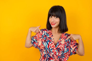 Çekici, duygusal, beyaz bir kadın tişörtünü gösterip gülümserken arka planda olumlu duygular ifade ediyor. Kız çok çalışmış, kaslarını göstermek istiyor.