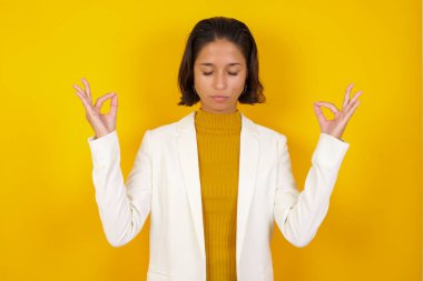 Meditasyon, din ve ruhani uygulamalar. Güzel, genç, esmer bir kadın sabah uyandıktan sonra yoga yapıyor, gözlerini kapalı tutuyor, parmaklarını Mudra jestinde tutuyor.. 