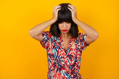 Genç ve güzel bir kadın başını arka planda tutuyor. Baş ağrısı, çaresiz ve stresli. Çünkü acı ve migren. Ellerini başının üstüne koy..