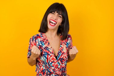 Güçlü, başarılı, kararlı, sıradan kıyafetler giyen, sıradan kıyafetler giyen, kollarını kaldıran, yumruklarını sıkan, hedefini sevinçle haykıran beyaz kadın portresi. Zafer, başarı ve başarı kavramı.