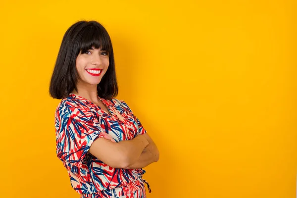 Pretty Caucasian lady standing against wall with arms crossed wearing casual clothes. Looking and smiling at the camera. Confident successful woman.