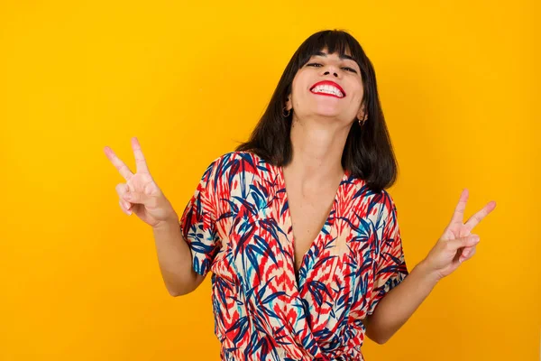 Neşeli kadın vuruşu iki eliyle barış ya da zafer işareti yapar, günlük kıyafetler giyer, serin hisseder dişli bir gülümsemesi vardır. İnsanlar ve vücut dili.