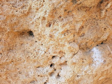 Çatlakları ve oyukları olan pürüzsüz bir taş parçası.