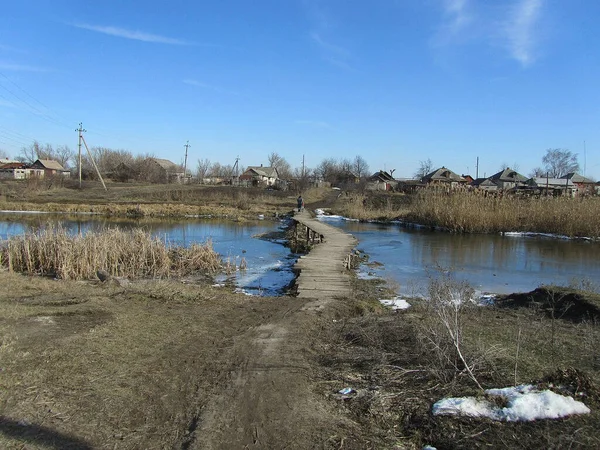 Kıyıdaki köy. Nehrin üzerindeki tahta köprü..