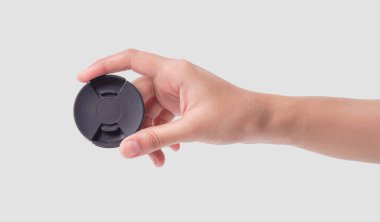 Temiz beyaz arkaplana karşı kameranın lens kapağını tutmak.