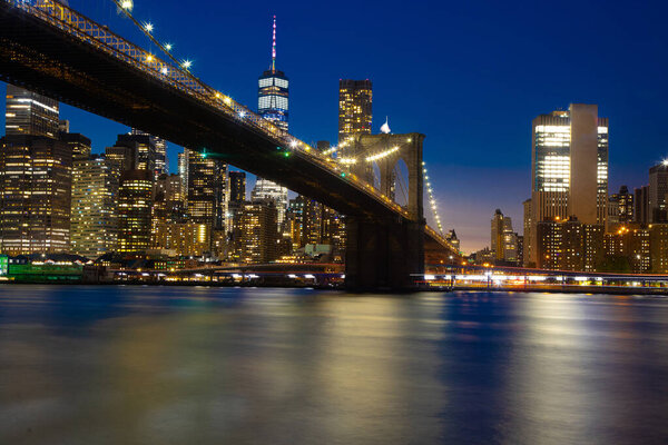 Brooklyn bridge at night with water reflection blue