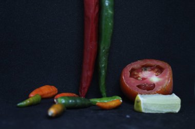 Biberli domatesler ve arka planda siyah limonlar.