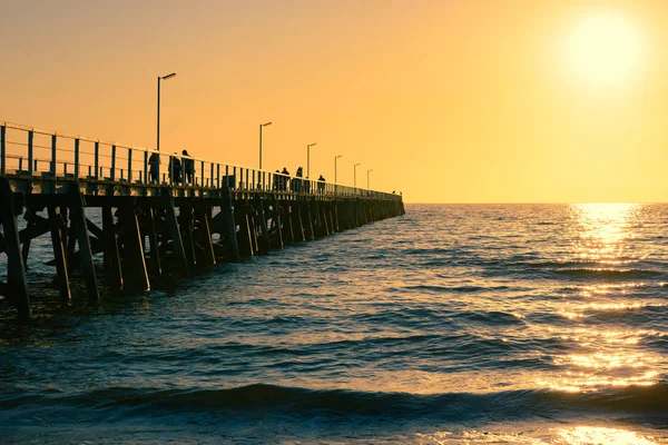 Jetty at sunset with some people