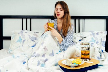 Genç kadın yatakta tabl üzerinde ilaç çok ile yatakta oturan