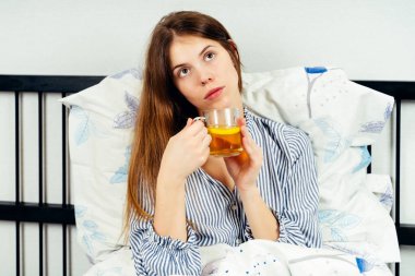 Genç kadın yatakta tek başına oturan ve te içme