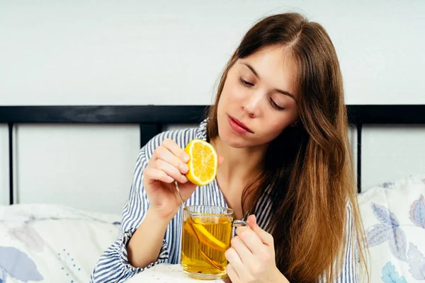 Bir fincan çayla yatakta tek başına oturan genç kadın