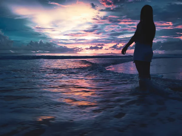 Gün batımında deniz kenarındaki dalgalarda güzel bir kız .