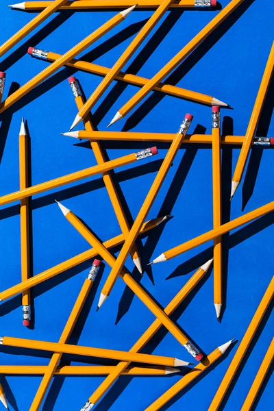 Pencils: pattern of orange pencils from above on blue background. Office and school concept