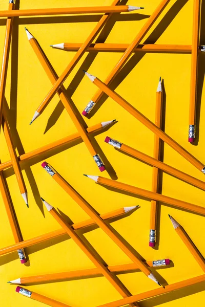 Pencils: pattern of orange pencils from above on yellow background. Office and school concept