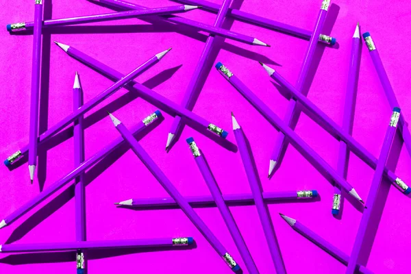 Pencils: pattern of purple pencils from above on pink background. Office, feminism and school concept