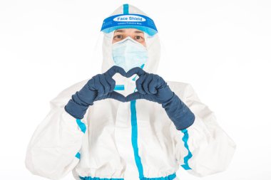 Koronavirüsle savaşmak için PPE giyen kadın doktor, beyaz arka planda eliyle kalp yapıyor. Savaşçı. COVID tıp konsepti