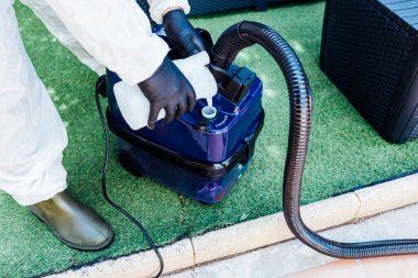 Bir evi COVID-19 'dan temizlemek için makineye dezenfektan kimyasal yükleyen bir adam.