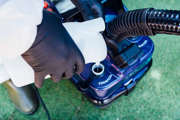 A man loading a disinfectant chemical into a machine to clean a house from COVID-19