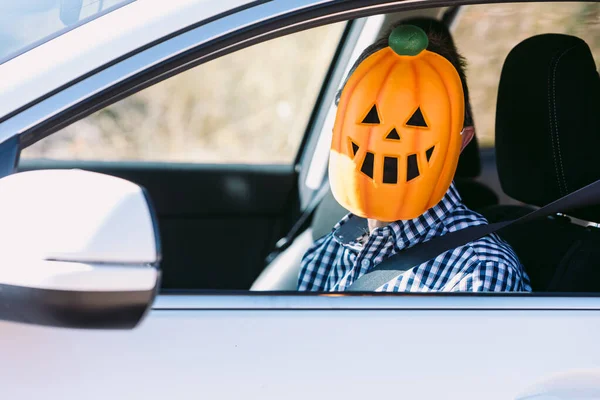Man inside a car with a pumpkin mask of jack o lantern Hallowwen