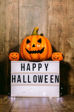 'Mutlu Cadılar Bayramı' mesajı ve ahşap arka planda küçük balkabakları olan ışık kutusu