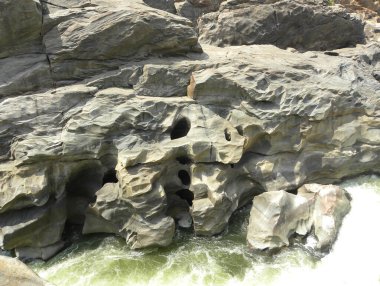 Gri renkli granit kayalıklardaki doğal delikler güçlü nehir suyu akıntısıyla oluşur.