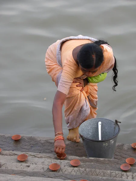 オレンジを身に着けている女性は Dev Deepavaliの機会に帽子のステップにオイルランプを配置するのを見ます — ストック写真