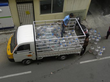 Beyaz renkli kamyon birçok plastik ambalajlı içme suyu şişesi taşıyor.