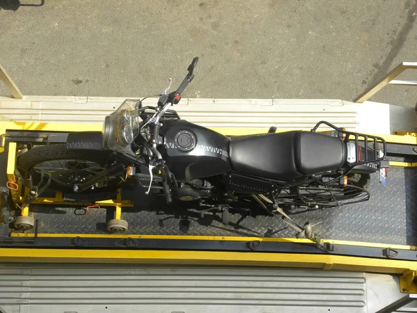 Çekici siyah renkli bir motosikleti çekiyor.