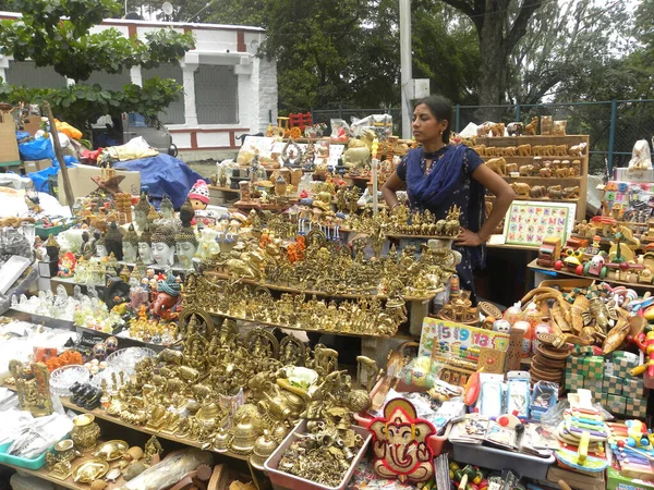 Nandi Bull Tapınağı yakınlarındaki dükkanda heykel, pooja eşyaları ve oyuncaklar satan Hintli bir kız.