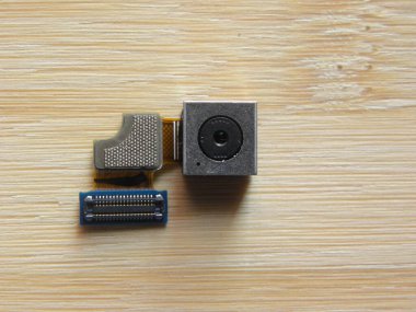 Smartphone camera module component kept on wooden table clipart