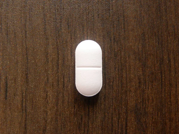 Malá Podlouhlá Bílá Tableta Léku Dřevěném Pozadí — Stock fotografie