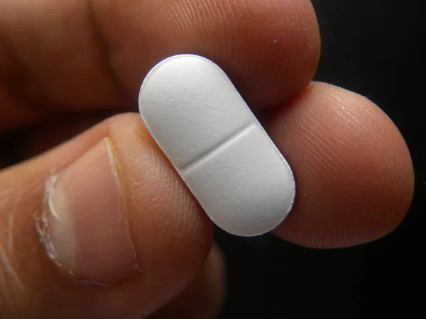 Рука Держит Небольшие Продолговатые Формы Белые Таблетки Лекарства — стоковое фото
