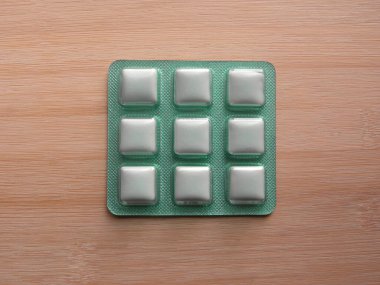 Beyaz ve yeşil sakız bandı ahşap masada duruyor.