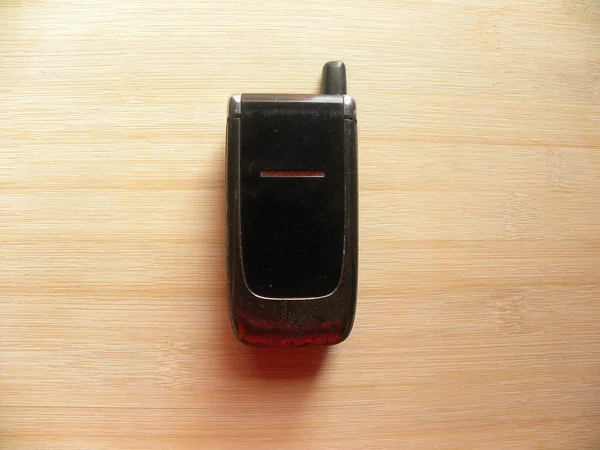 Old black color flip phone kept on wooden table