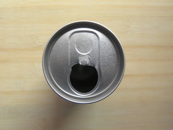 Top view of open drink can without pop tab kept on wooden table