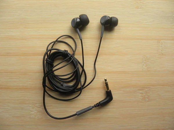 木製テーブルの上の黒い色の耳のヘッドフォン — ストック写真
