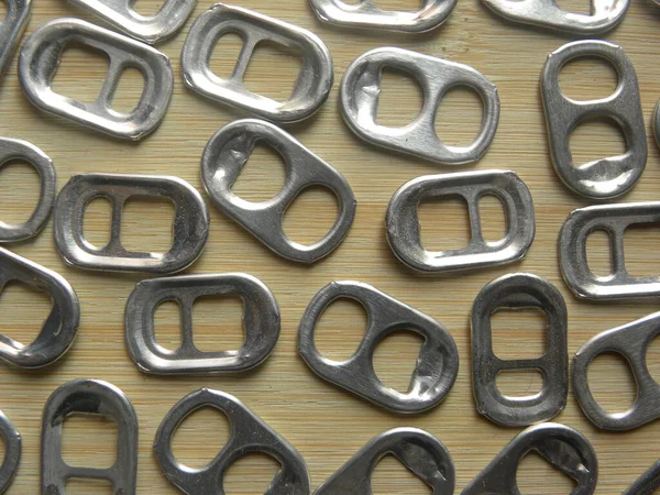 Small pop tabs of drink can kept on wooden table