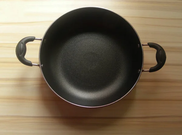 Siyah renkli sopa olmayan Karahi, ahşap masada duran tencere.