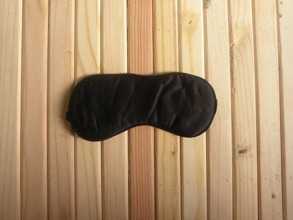 Black color sleep mask kept on wooden table