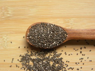 Beyaz ve siyah renkli çiğ Chia tohumları veya tahta kaşıkta Salvia Hispanikleri