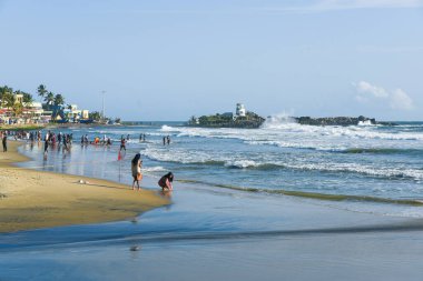 Kerala, Hindistan - 08 Eylül 2019: Kovalam plajı ve Vizhinjam deniz feneri. İnsanlar Trivandrum 'da deniz kıyısında eğleniyor..