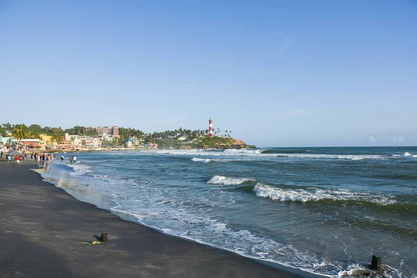 Kerala, Hindistan - 08 Eylül 2019: Kovalam plajı ve Vizhinjam deniz feneri. İnsanlar Trivandrum 'da deniz kıyısında eğleniyor..