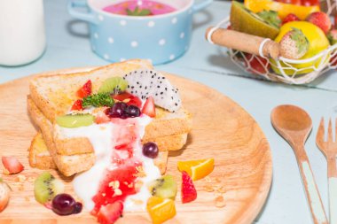 Kızarmış ekmek ve meyveli yoğurt, kızarmış yumurta ve ahşap tavada..