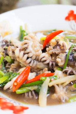 Ahşap üzerinde kızarmış kalamar biberi soğanı ve maydanoz tabağı..